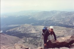 Jocelyn scrambling from the steep homestretch, with a valley in the background