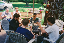 Seated with food, around a patio table.