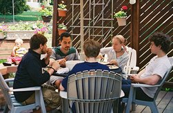 Seated with food, around a patio table.