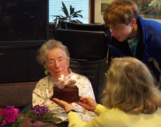 Carola hold the birthday cake for Mother Turner, while Philip helps blow out the candles