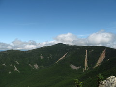 mountain scarred with rockslides, fluffy clouds